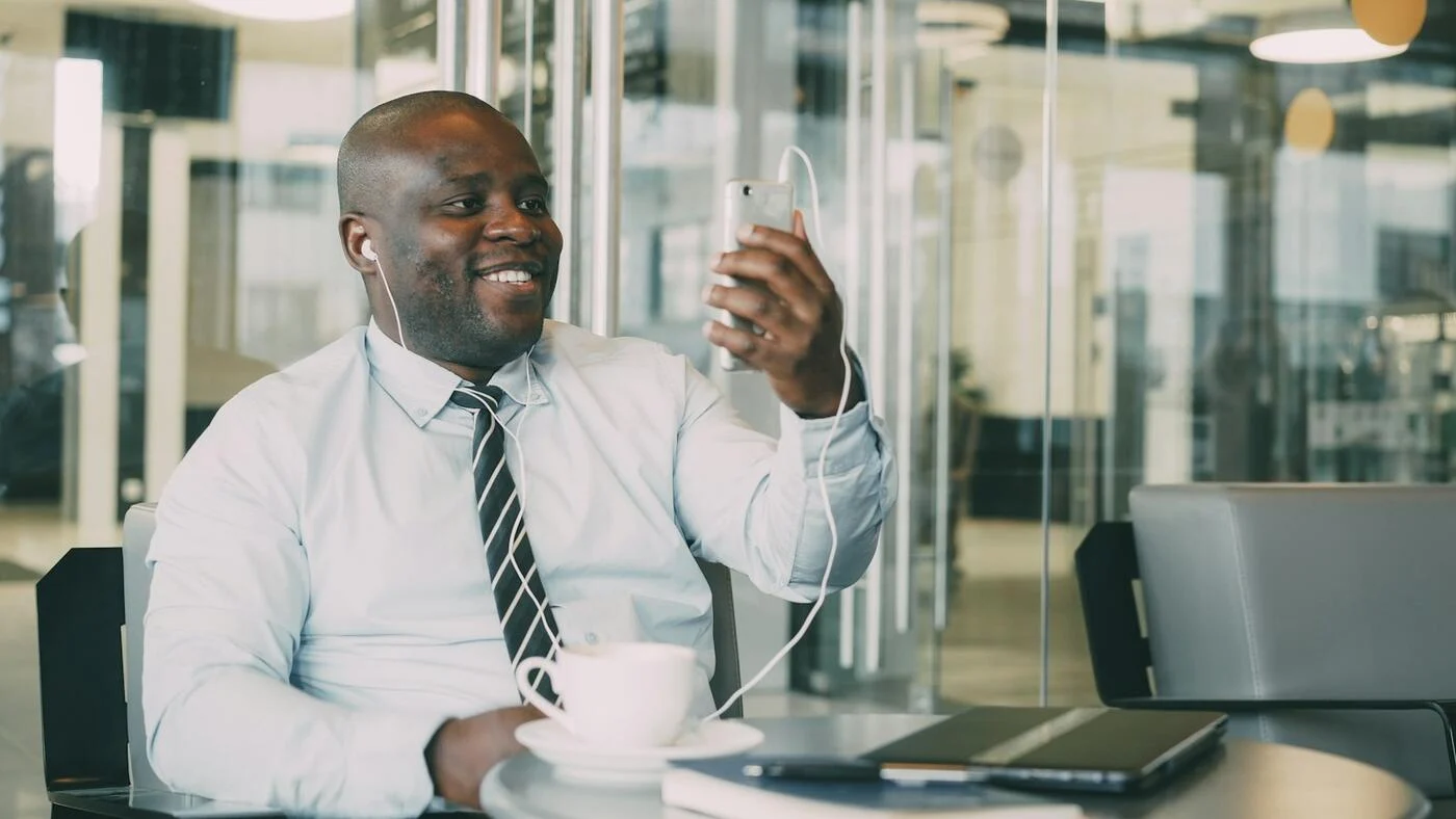 A smiling businessman on a call in a glass-walled office
