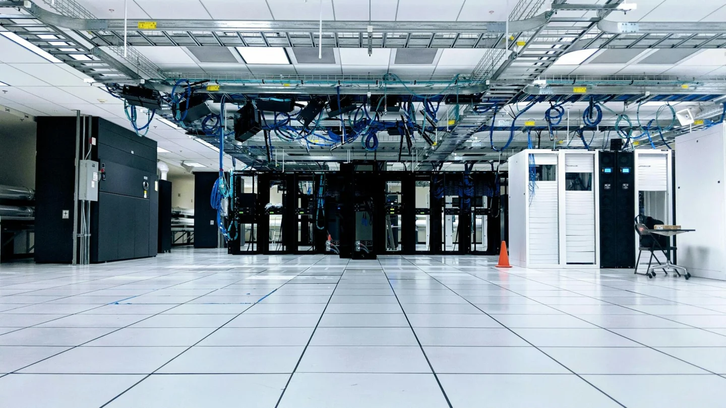 A modern data centre with rows of server cabinets under network cabling