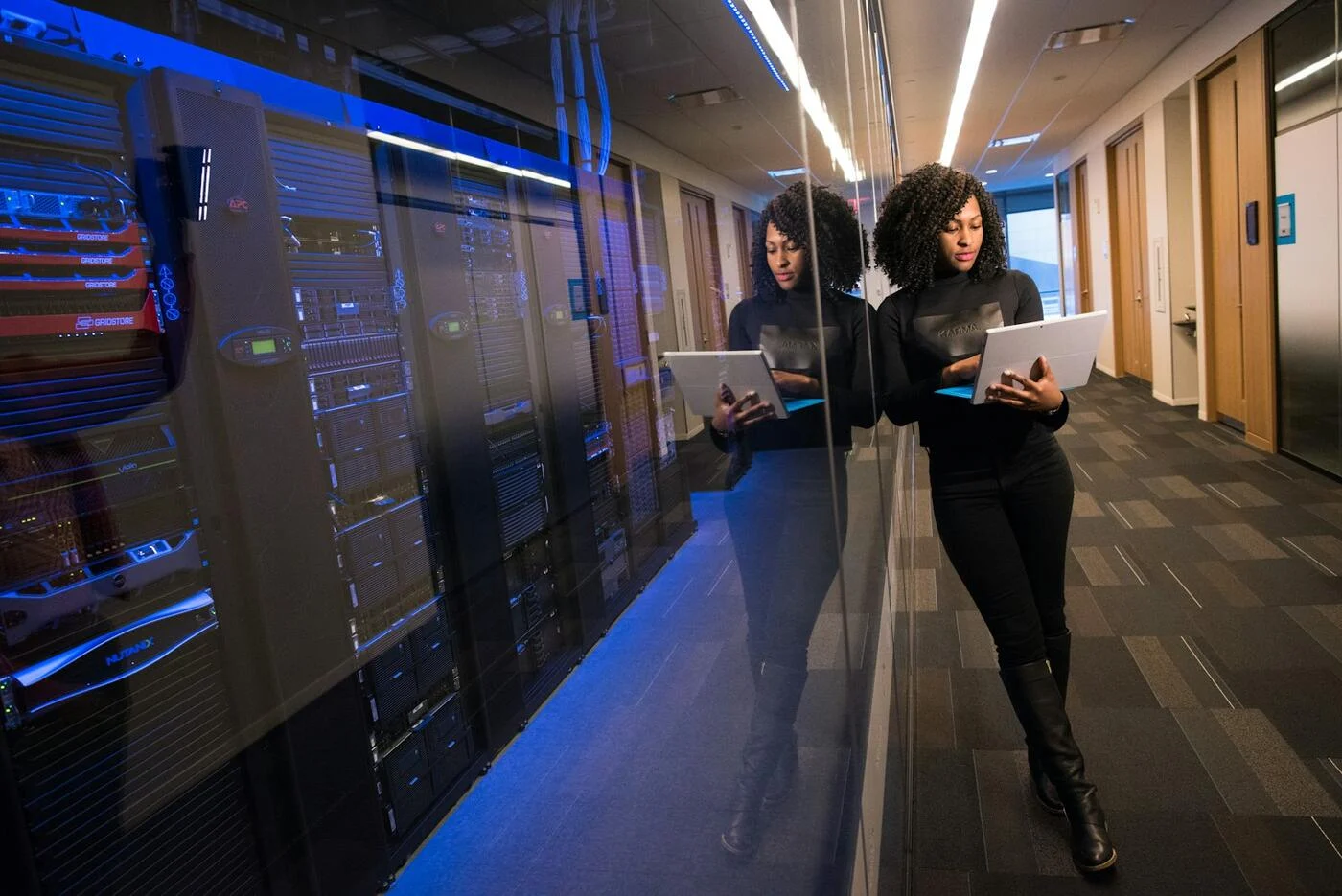 Two IT professionals with laptops in a server corridor