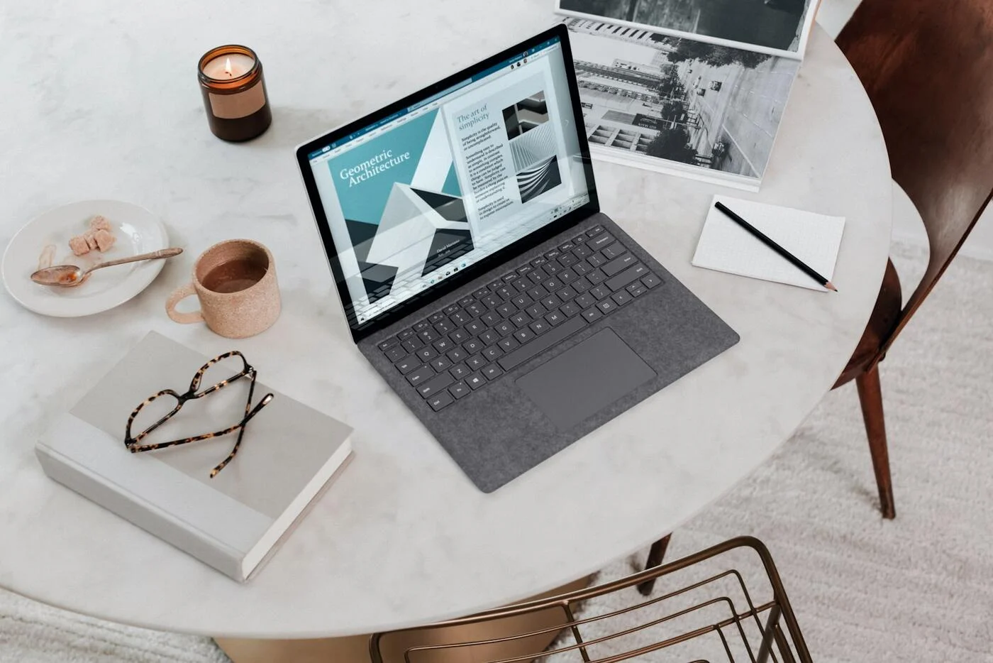 A business laptop on a desk beside a notebook and coffee